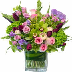 Mixed pink, purple, and green flowers arranged in a glass vase