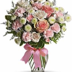 Pink and white rose bouquet in a clear glass vase with a pink ribbon