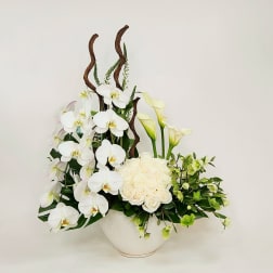 White orchids, roses, and calla lilies in a white bowl vase