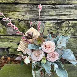 Blush roses in a clear glass vase with blue-gray foliage and pink pussy willow stems