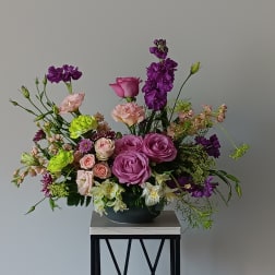 Mixed bouquet of pink and purple flowers in a low black bowl