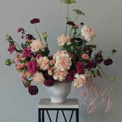 Loose bouquet of pink and cream flowers in a white vase