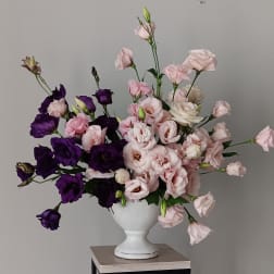 Pink and purple flowers arranged in a white vase