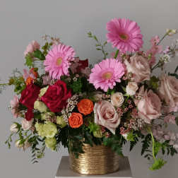 Mixed pink and peach flowers in a gold vase