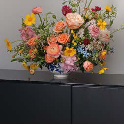 Mixed bouquet in a blue-and-white vase with pink, peach, and yellow flowers