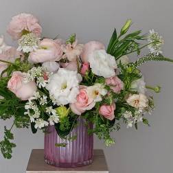 Pink and white flower arrangement in a purple glass vase