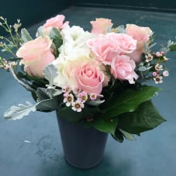 Pink and white roses arranged in a dark vase