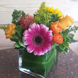 Colorful bouquet with a pink gerbera daisy in a glass cube vase