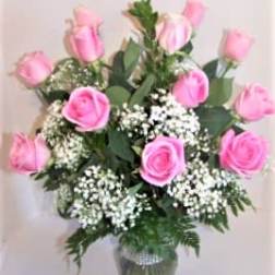 Pink roses arranged in a clear glass vase with white filler flowers