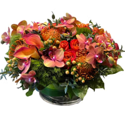 Orange and pink floral arrangement in a glass bowl vase