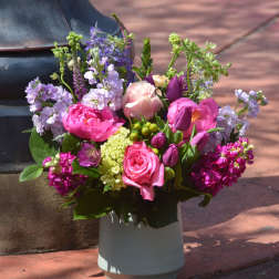 Colorful pink and purple flower arrangement in a white ceramic vase outdoors
