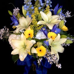 Bouquet of cream lilies, blue flowers, and yellow daisies with a blue ribbon
