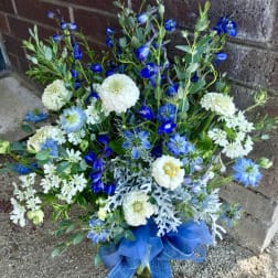 Blue and white mixed flower arrangement with ribbon at the base