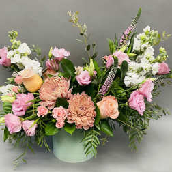 Pink and peach floral arrangement in a pale green vase