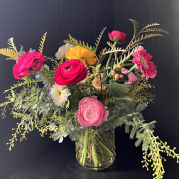 Bright mixed bouquet in a clear glass vase with pink, yellow, and white blooms