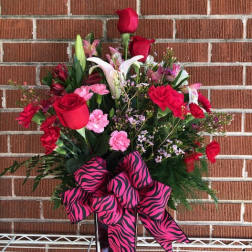 Red and pink mixed flower arrangement with a zebra-print ribbon in a vase