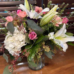 Bouquet of white lilies, pink roses, and white hydrangea in a glass vase