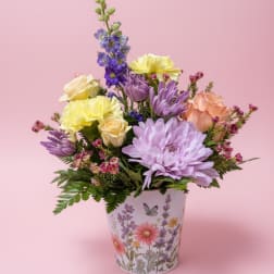 Mixed pastel flowers arranged in a decorative floral pot