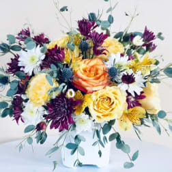 Bouquet of yellow and purple flowers in a white container