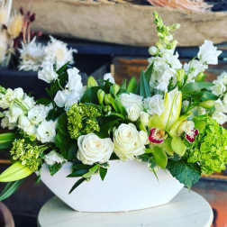 White and green floral arrangement in a white bowl vase