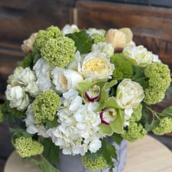 White and green floral arrangement in a round box