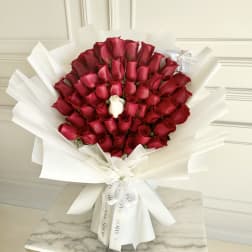 Bouquet of red roses wrapped in white paper with one white rose