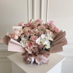 Pink and white bouquet with roses and orchids wrapped in blush paper