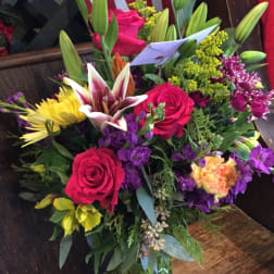 Mixed bouquet of roses, lilies, and chrysanthemums in a glass vase