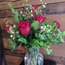 Bouquet of red roses and white filler flowers in a clear glass vase