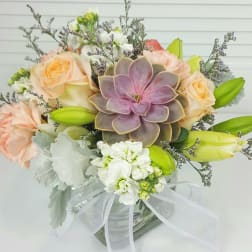 Bouquet with roses, lilies, and a succulent in a glass vase