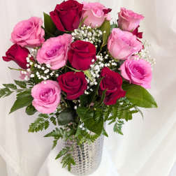 Tall arrangement of red and pink roses with baby's breath in a silver textured vase