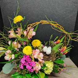 Floral arrangement with pink blooms, yellow chrysanthemums, and a twig nest with eggs