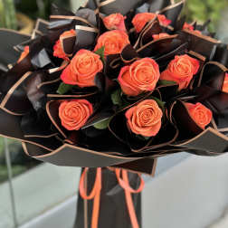 Bouquet of orange roses wrapped in black paper with peach trim