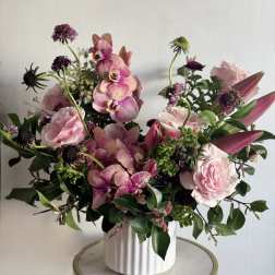 Pink roses and orchids arranged in a white vase