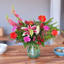Mixed bouquet with pink lilies and red roses in a glass vase