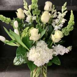 White roses and snapdragons arranged in a clear glass vase