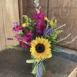 Sunflower bouquet with bright pink and purple flowers in a glass vase