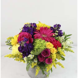 Colorful bouquet of roses, gerbera daisies, and mixed blooms in a gray vase