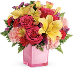 Pink and yellow floral arrangement in a pink glass vase