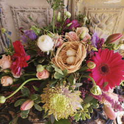 Mixed bouquet with pink gerberas, roses, and a small nest with eggs