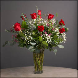 Red roses arranged in a clear glass vase with white filler flowers