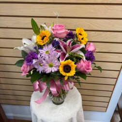 Mixed bouquet in a glass vase with pink, yellow, purple, and white flowers