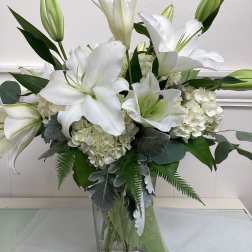 White lilies and hydrangeas arranged in a clear glass vase