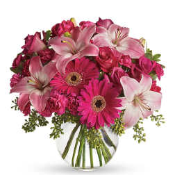 Pink lilies, gerbera daisies, roses, and carnations in a glass vase
