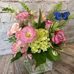 Pink mixed bouquet with green hydrangea and a blue butterfly pick in a clear glass cube vase