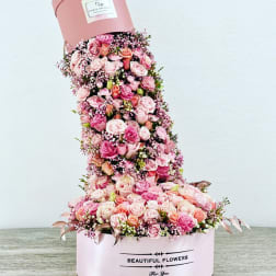Tall pink hatbox arrangement of roses and baby’s breath