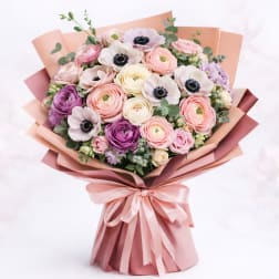 Bouquet of pastel flowers wrapped in pink paper with a satin ribbon