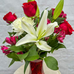 Red roses and white lilies in a red glass vase
