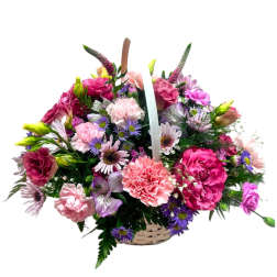 Basket arrangement of pink carnations, roses, and purple daisies with mixed pastel flowers.