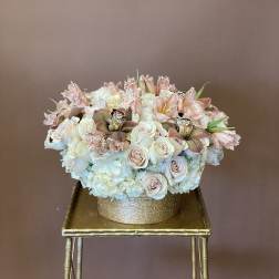 Blush and white floral arrangement in a gold round box